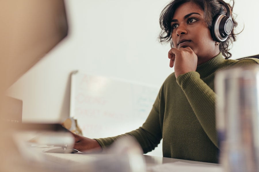 Employee doing research on a computer with headphones on