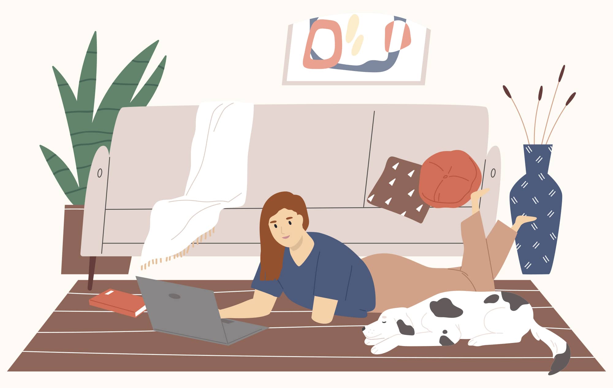 Redheaded woman with a limb difference lays on the floor working on her laptop while a dog sleeps next to her.